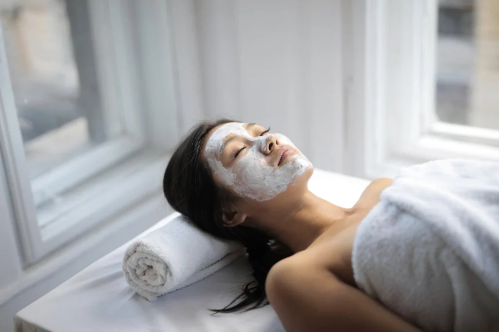 Woman relaxing with a white facial mask during spa skincare treatment